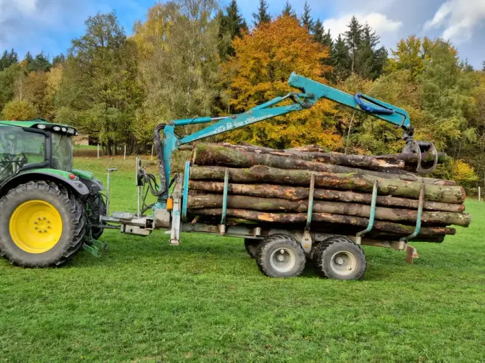 Traktor mit Kran-Rückewagen voll Stammholz