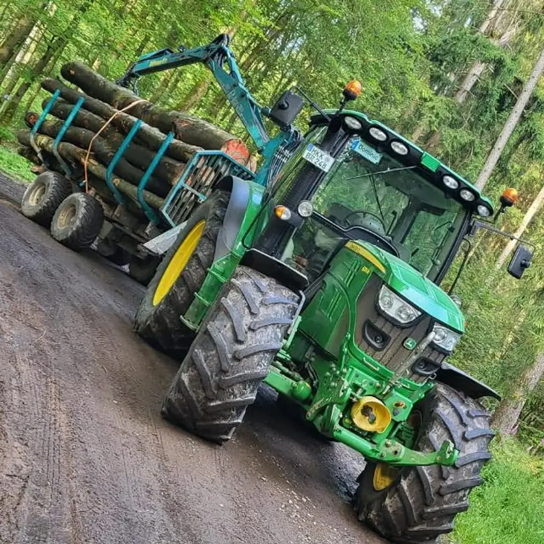 Traktor mit Kran-Rückewagen, beladen mit Stammholz, auf einem Waldweg im Spessart
